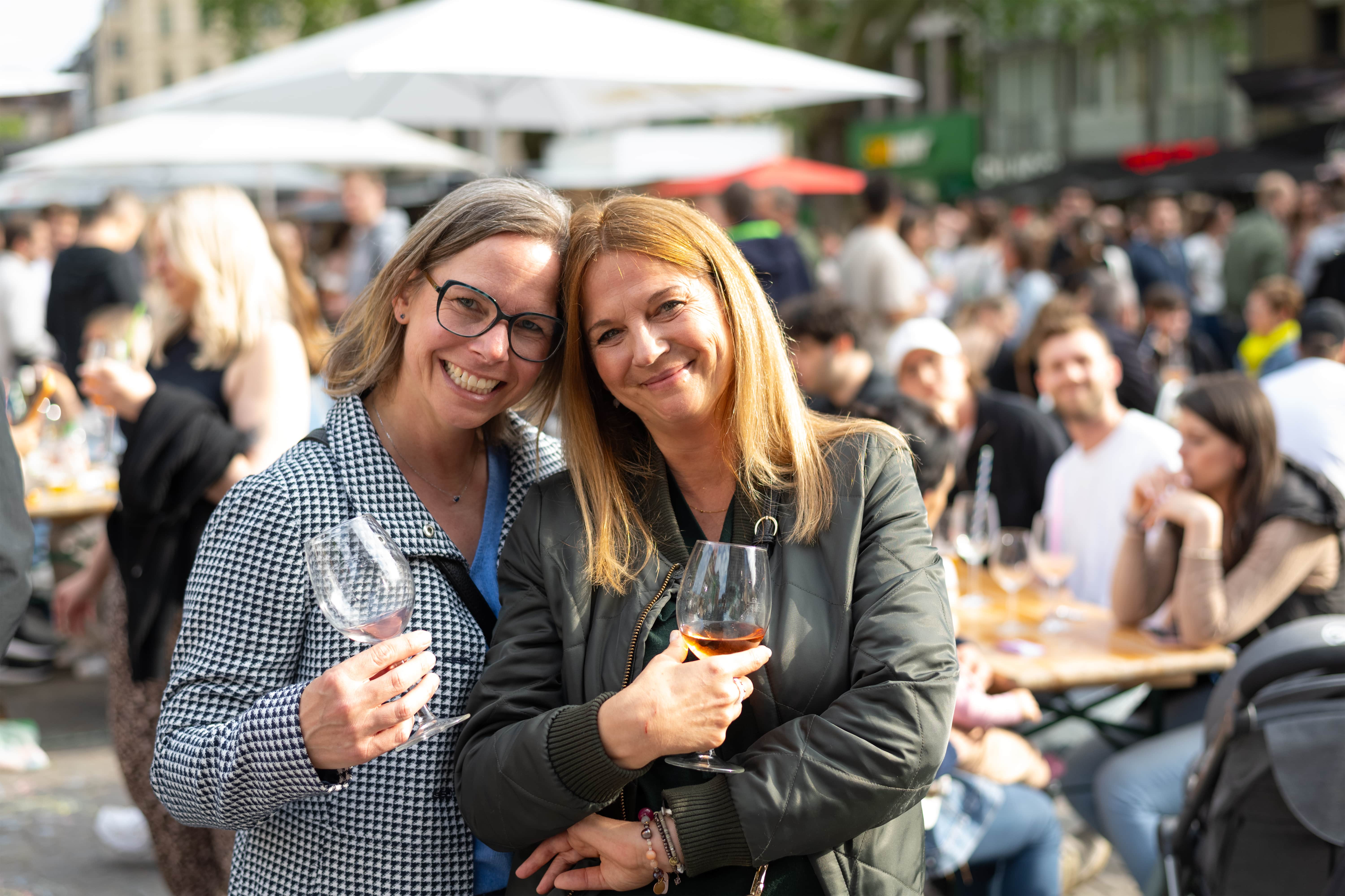 Zwei Frauen genießen den Feierabend mit einem Glas Wein auf dem Feierabendmarkt am Chlodwigplatz in Köln.