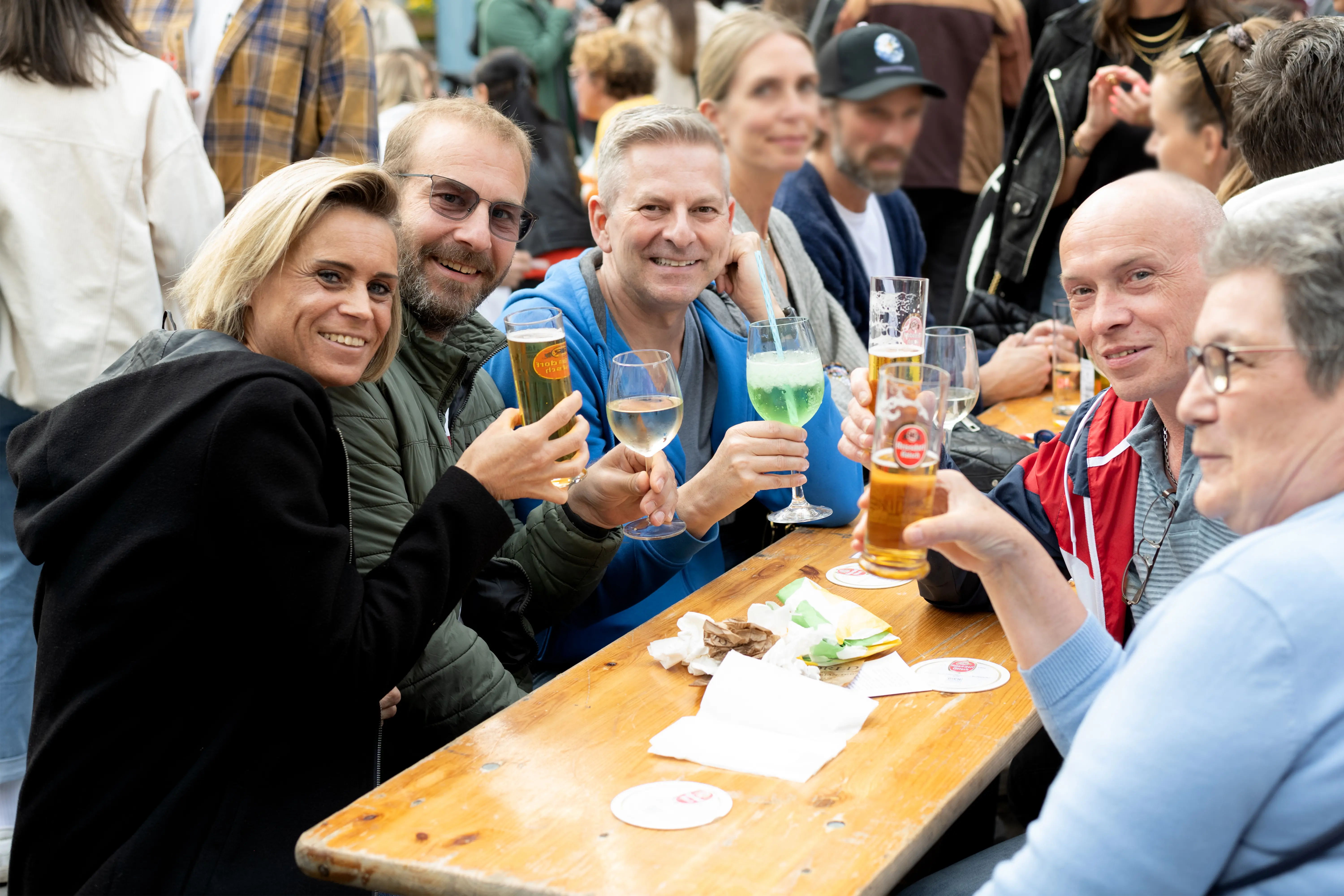 Eine Gruppe von Freunden stößt mit Kölsch, Wein und Cocktails auf dem Feierabendmarkt am Chlodwigplatz in Köln an.