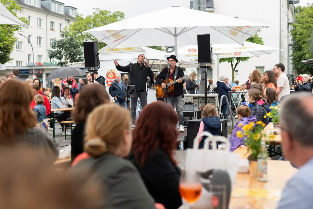 Björn Heuser und ein Sänger treten live auf dem Feierabendmarkt am Hermeskeilerplatz in Köln auf.