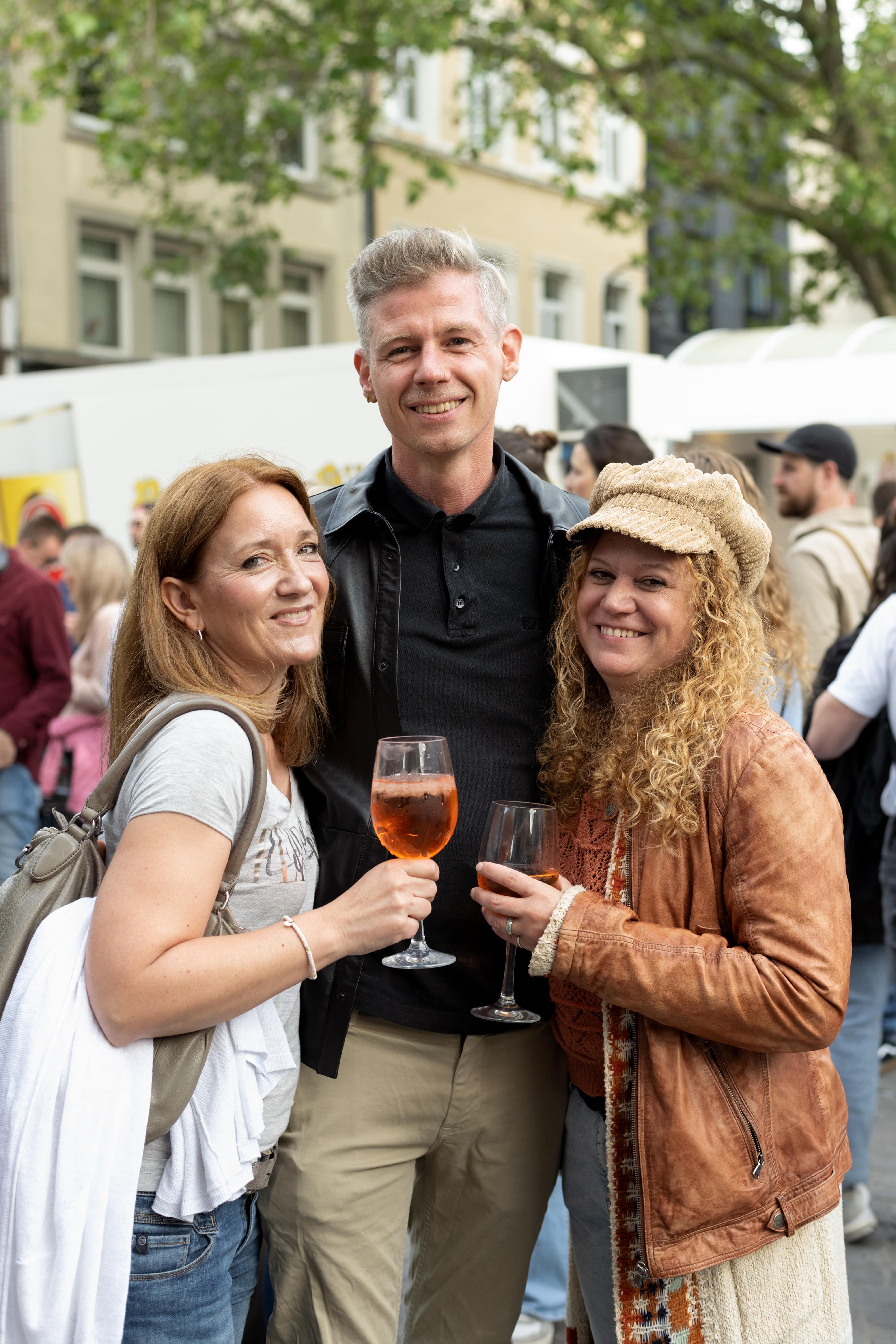 
Drei Freunde mit Aperol Spritz und Kölsch auf dem Feierabendmarkt in Köln
