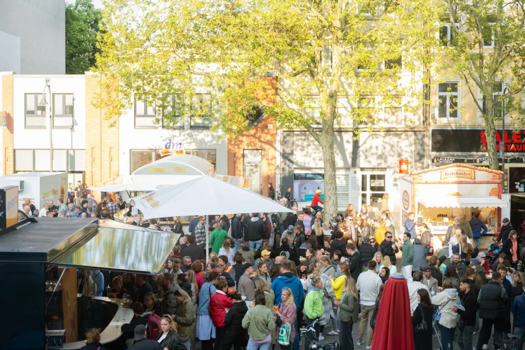 Blick über den Chlodwigplatz beim Abendmarkt mit entspannter Stimmung und Lichterketten