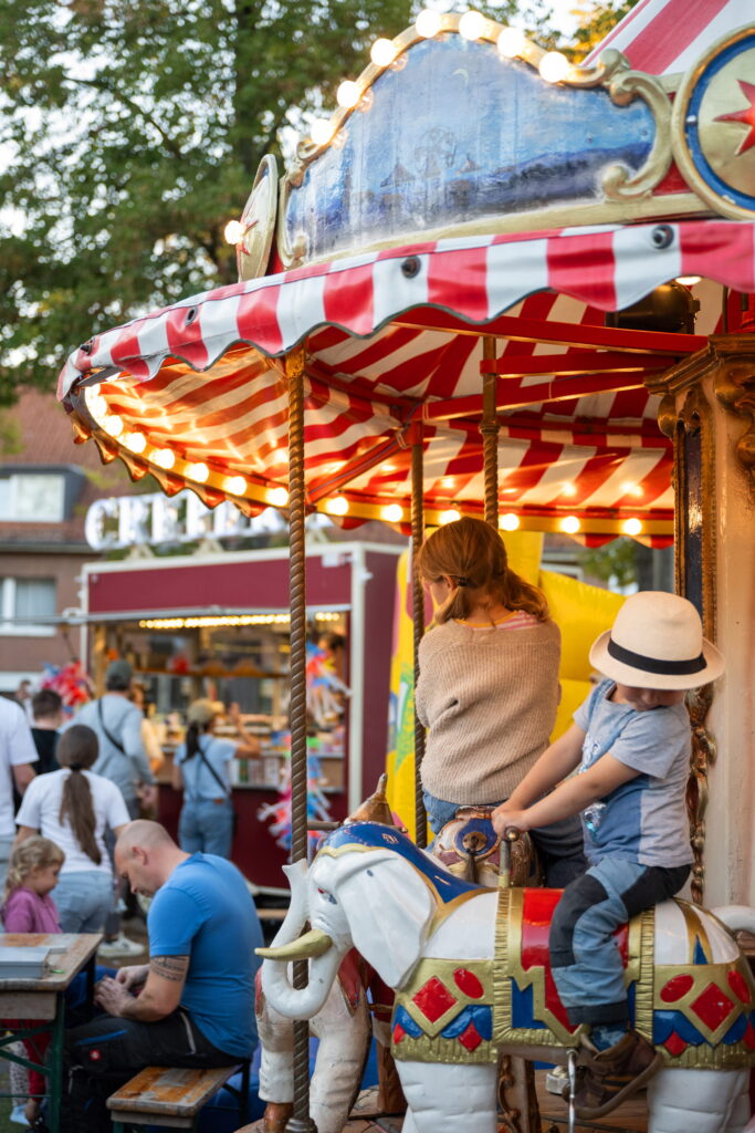 Kinder im beleuchteten Elefantenkarussell auf dem Feierabendmarkt am Marktplatz Sürth
